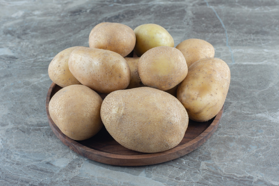 A small pile of red-skinned regular potatoes on a light wooden surface